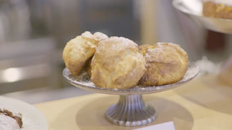 organic muffins laying on a silver food platter stand with more backing goods in the background