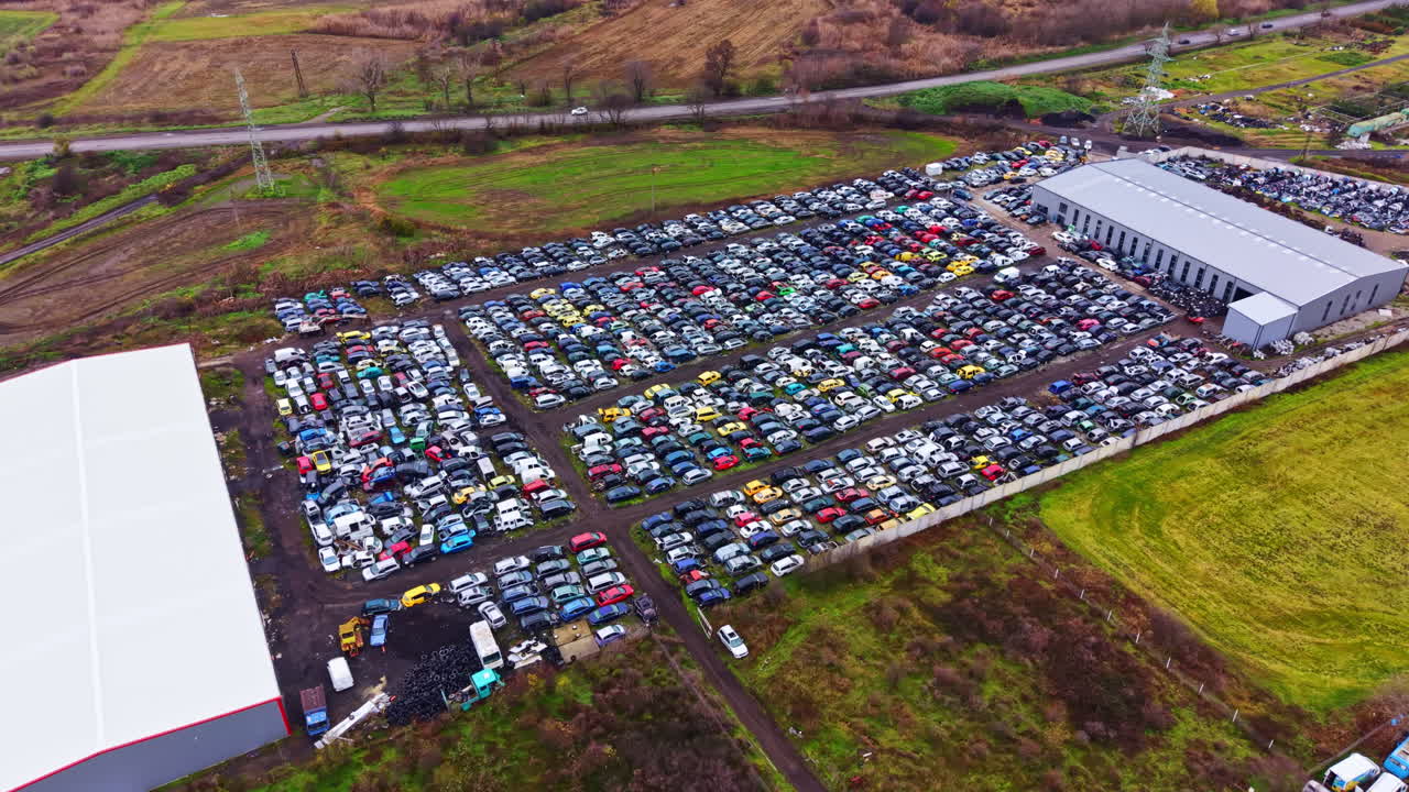 Gran zona de aparcamiento con muchos coches cerca de un almacén en un día despejado en una zona industrial