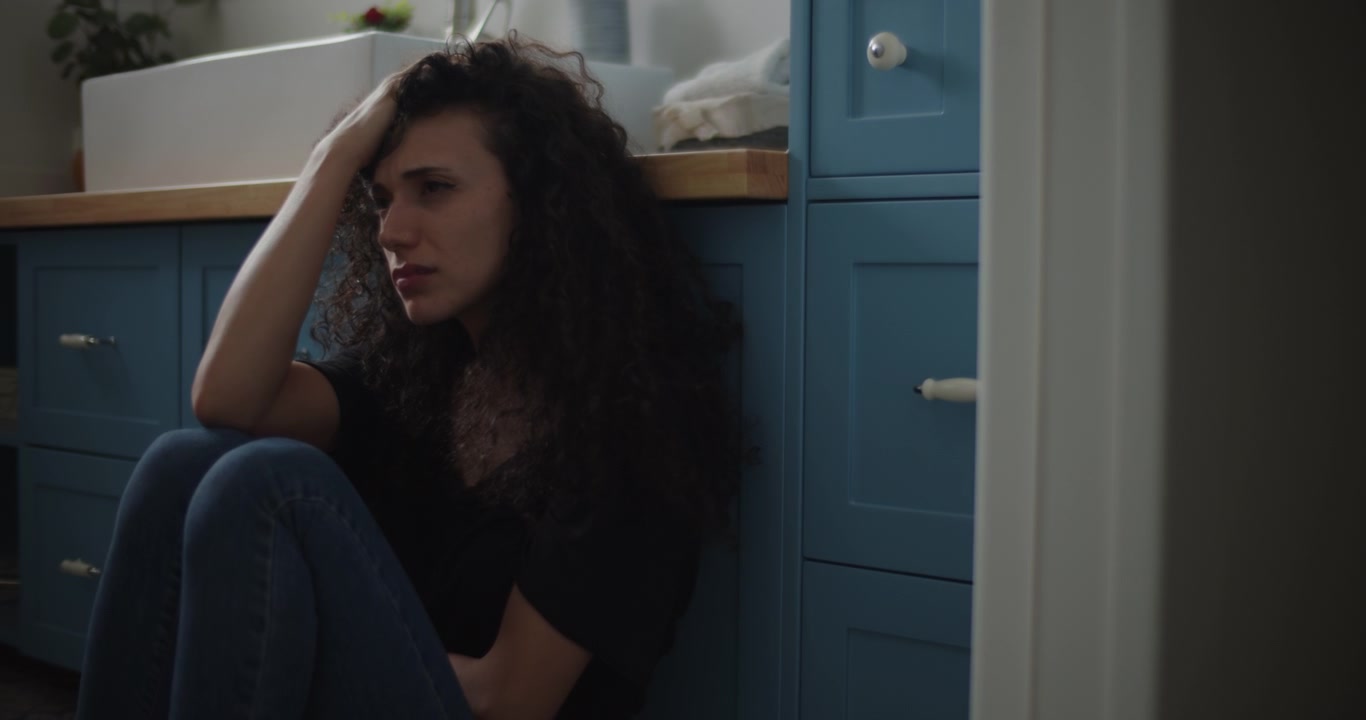 Donna depressa che si siede sul pavimento