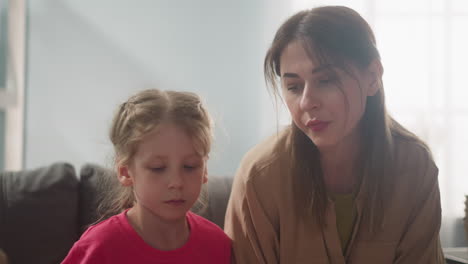 concentrated mother and daughter look at boy in living room