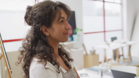 Biracial-woman-smiles-in-a-bright-office,-with-copy-space