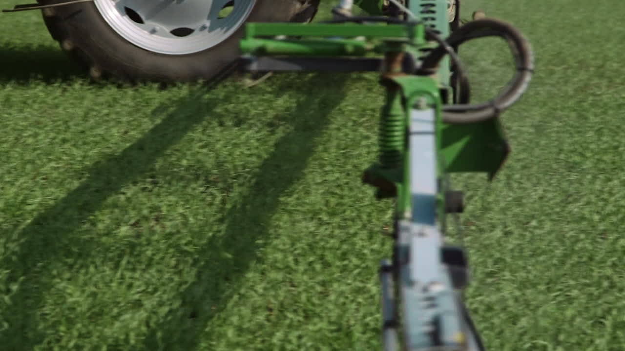 Trattore agricolo che transita davanti alla telecamera e irrora pesticidi con l'atomizzatore.