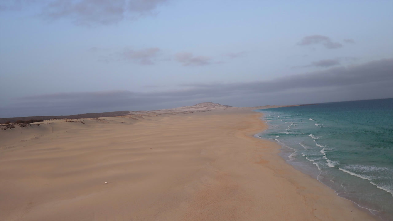 Spinning wheel view of Chaves beach, sandy beach and green ocean background desert,on the left wooden store with Cape Verde flag, summer concept, Boa Vista, Cape Verde.