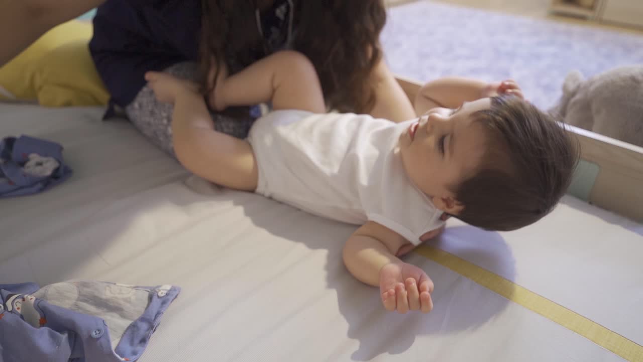 The mother taking off her baby's dress.