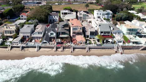 Celebrity-homes-lines-shoreline-of-sandy-Malibu-beach,-aerial-view-during-the-day