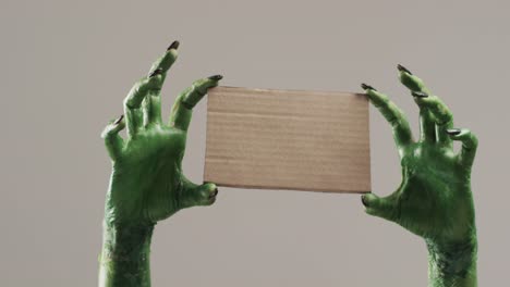 video de halloween monstruo verde manos sosteniendo tarjeta con espacio de copia en fondo gris