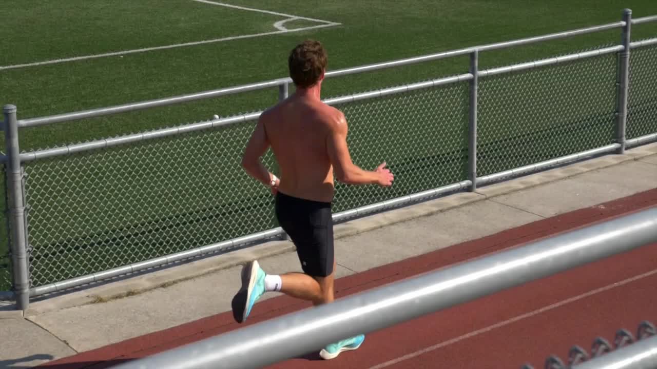 movimiento lento de un tipo sin camisa con cuerpo muscular corriendo en una pista deportiva