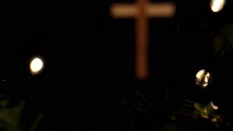 slow rack focus of a wooden cross ornament hanging on a christmas tree