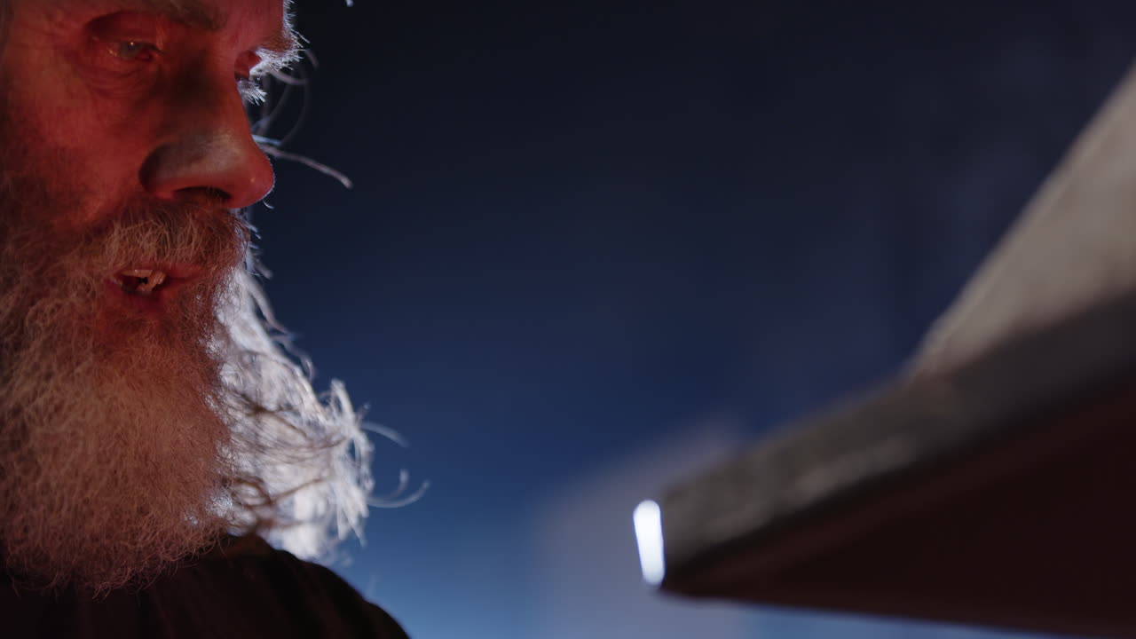 A blacksmith finishes heating his iron and returns to the anvil, closeup face