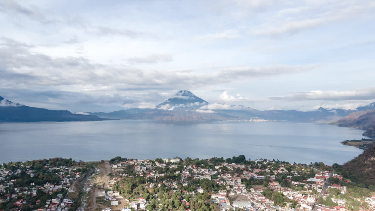 hiperlapso aéreo lento en la mañana sobre la ciudad en pana con el lago atitlán y la montaña al fondo
