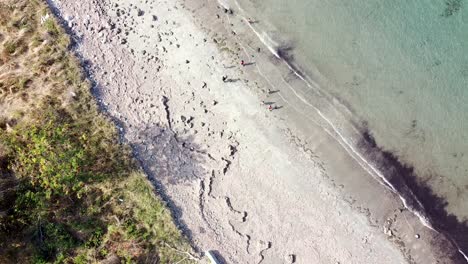 Aerial-drone-of-people,-children,-kids-playing-on-the-beach-on-remote-tropical-island-Timor-Leste,-South-East-Asia