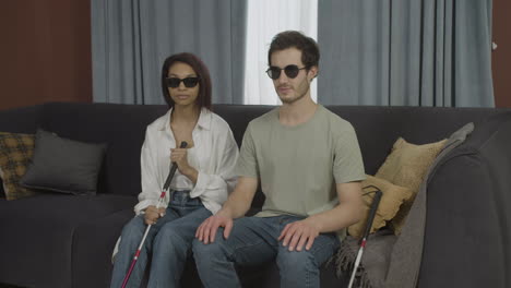 front view of blind friends sitting on a sofa in a flat