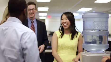 a joyful office interaction around the water cooler: colleagues engaging and sharing laughter in a bright workplace environment