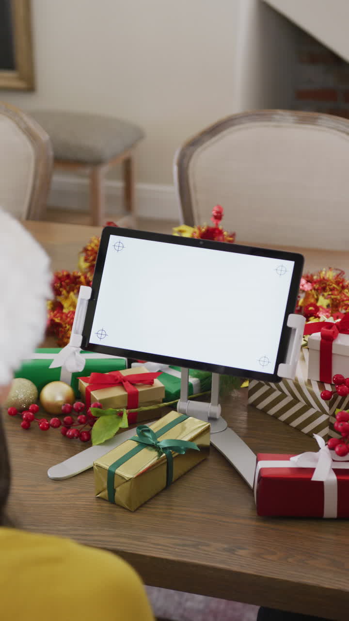 una mujer biracial en el sombrero de santa hace una llamada de video de navidad en una tableta, con espacio para copiar