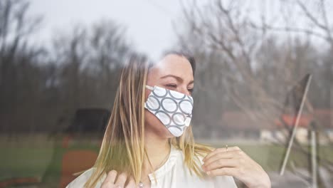 woman looking through window puts on face mask