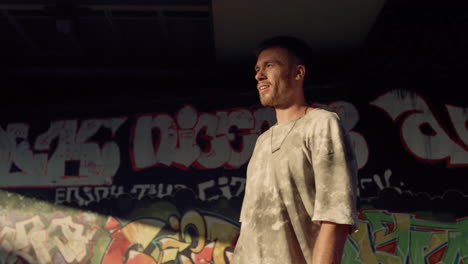 Smiling-teenager-roller-skating-at-skatepark-with-graffiti-wall-background.