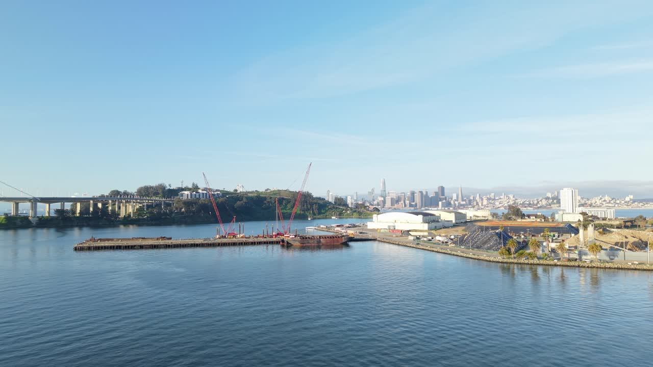Aerial footage captures Treasure Island's unique shape nestled in the Bay, flanked by calm water and distant bridges.