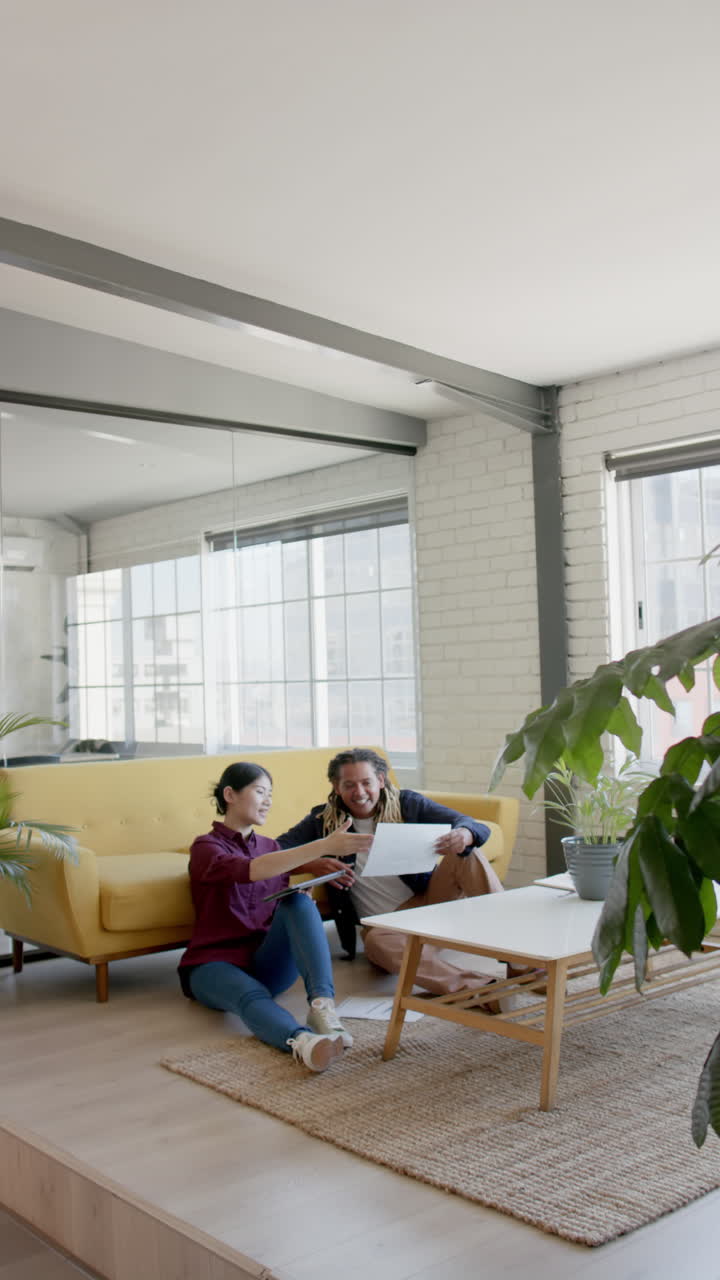 Vertical video of happy diverse business people sitting and discussing work