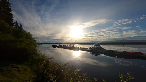 morning time lapse sunrise at lake while people gear up on a dock for a day on the lake for fishing, kayaking, boating, and canoeing