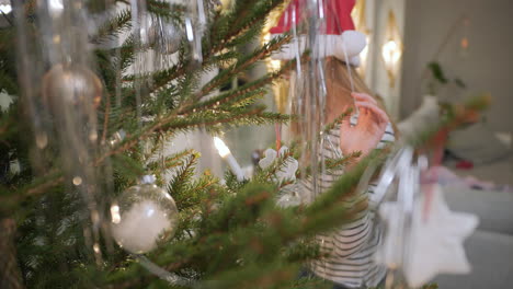 la niña está ayudando a decorar el árbol de navidad.