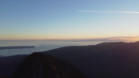 hermosa puesta de sol sobre las montañas con la bahía del puerto con los barcos y la ciudad en la distancia