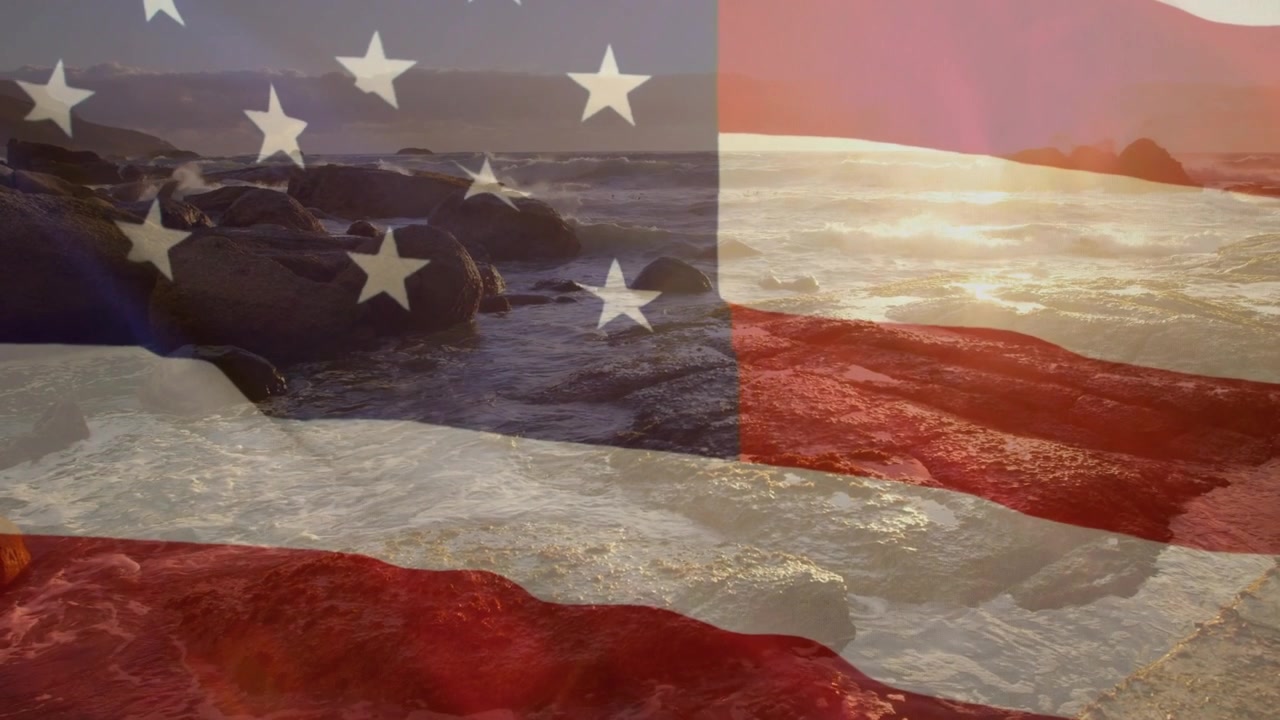 Saat matahari terbenam, hamparan bendera AS beriak di atas pantai berbatu saat matahari bergerak ke kanan, membangkitkan patriotisme yang tenang
