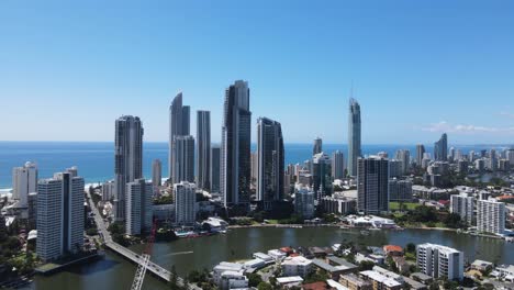 Vista-Aérea-Del-Río-Nerang-Con-El-Icónico-Horizonte-Del-Paraíso-De-Los-Surfistas-De-Gold-Coast-Elevándose-Sobre-El-Océano-Azul