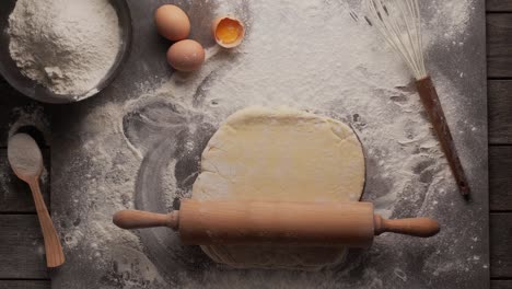 magic concept - a rolling pin itself rolls out the dough on the kitchen table against the backdrop of flour, eggs and a whisk. looped video.