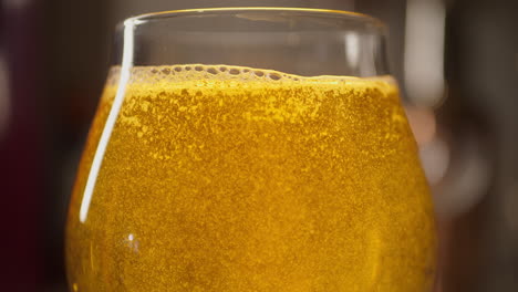 close up of craft beer being poured in to a tulip glass, light background