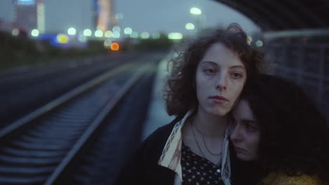 girls embracing at train station in evening