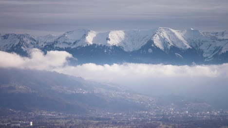 La-Cordillera-Cubierta-De-Nieve-Se-Eleva-Sobre-El-Valle-Densamente-Poblado-Mientras-Las-Nubes-Giran-Debajo