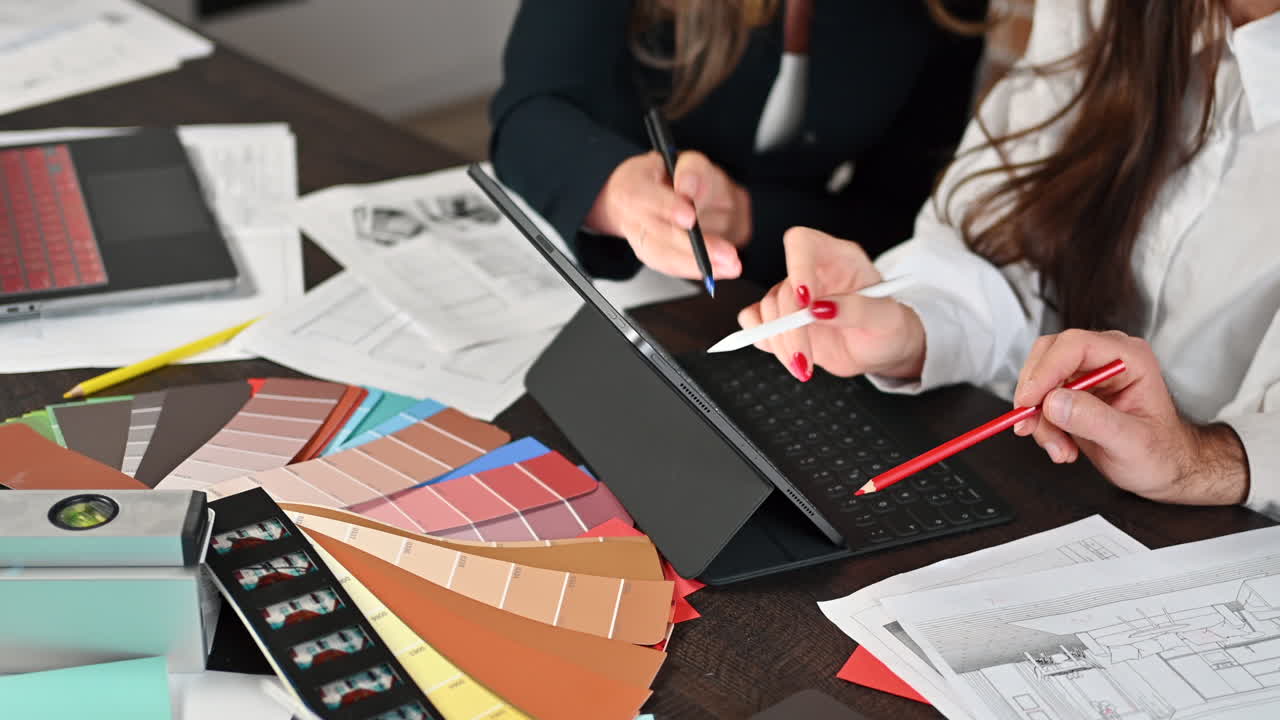 Coworkers analyzing a building plan on a tablet at a table in an office