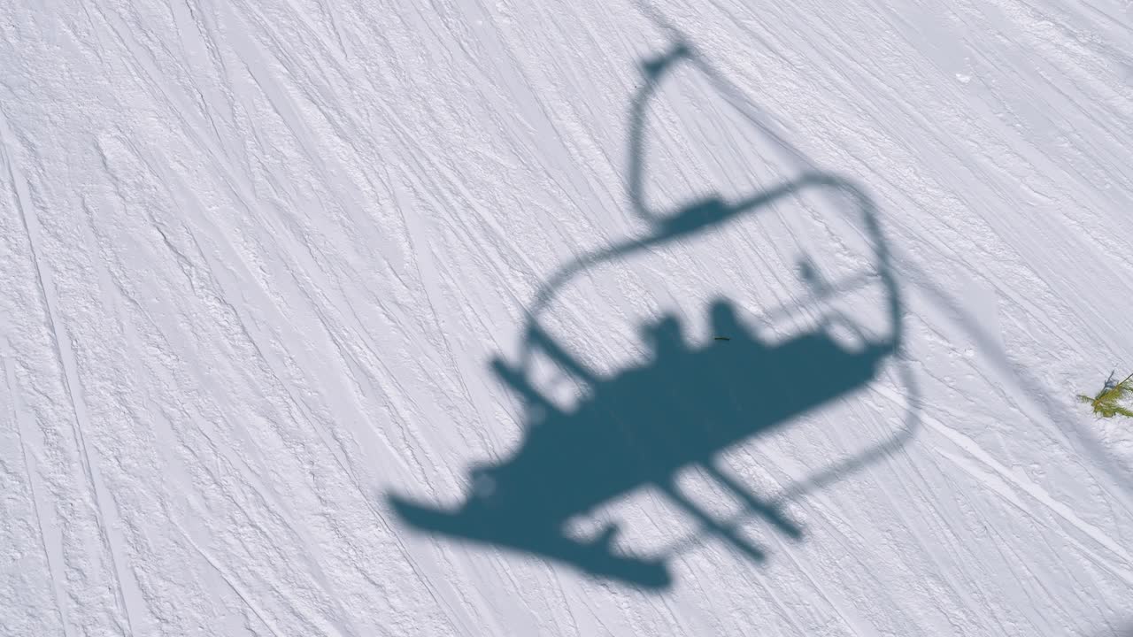 산악 스키 경로를 따라 스키 선수와 스노우보더와 함께 의자 엘리베이터에서 눈 속의 그림자