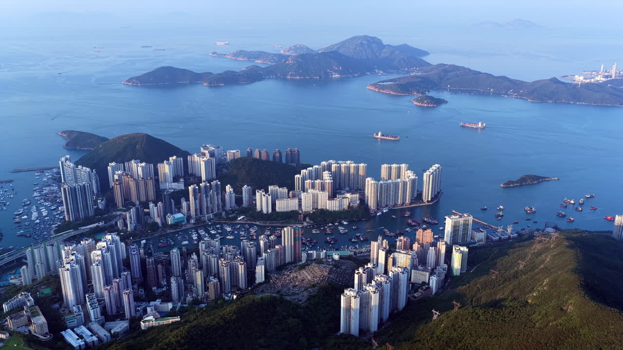 Cinematic aerial view of Hong Kong skyline shrouded in mist at blue hour, with glowing skyscrapers and Victoria Harbour fading into a moody, atmospheric twilight