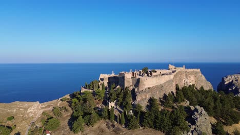 acropolis of lindos in rhodes, greece with houses and mediterranean sea during the day filmed with the drone