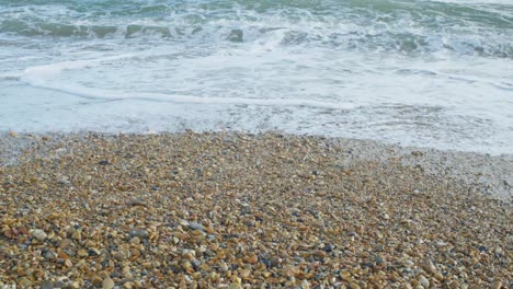 4k slow motion cinematic footage of waves hitting rocks on a pebble beach