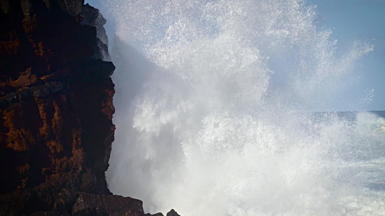 grandes olas ruedan en la costa de hawaii en cámara lenta y rompen a lo largo de una costa escarpada