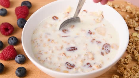 revolviendo un tazón de cereal recién hecho con granola y fruta