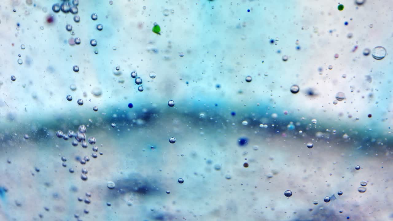 유리 뒤에 잉크가 있는 기름과 물에 있는 거품