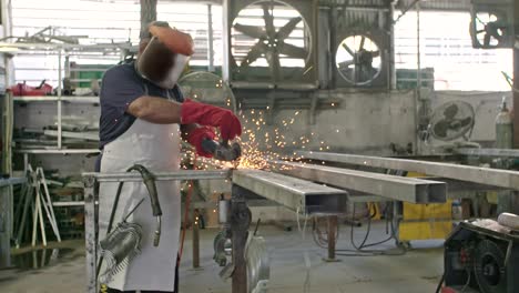 slow motion of a worker using metal grinder with sparks flying at a metal shop