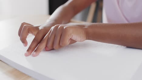 midsection of african american girl reading braille, slow motion