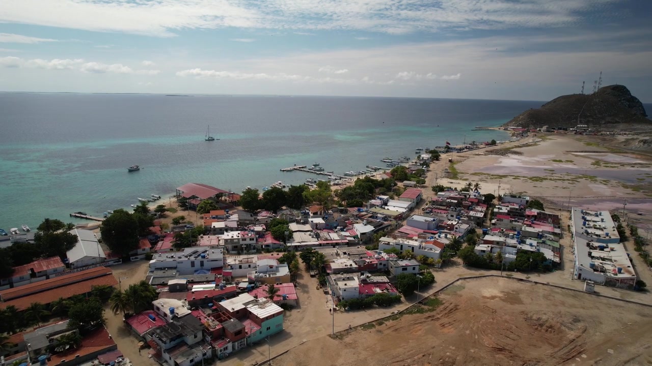 Villaggio costiero vicino al Mar Caraibico turchese visto dall'alto con barche ancorate al largo.