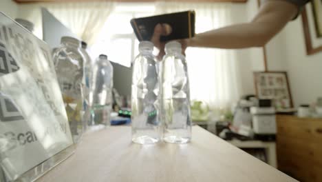 Buying-bottled-water-using-a-touchless-or-contactless-payment-bar-code-system-at-a-local-café---isolated-close-up