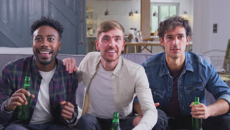 disappointed multi-cultural group of male friends watching sports game on tv at home as team loses