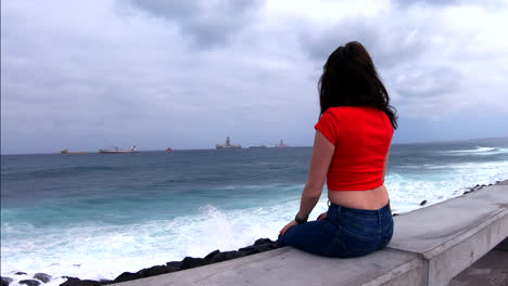 Girl-sitting-on-boulevard-watching-ships-on-the-sea