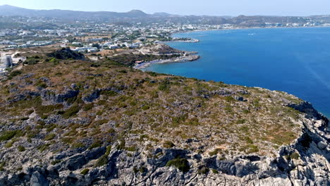 aerial view tilting over a cliff, revealing the faliraki coastline, in sunny rhodes