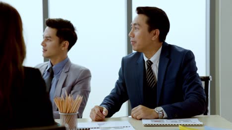 group of asian businessmen meeting to plan business in stock market, real estate by presenting business documents marketing information in modern meeting room. online investment strategy. white collar