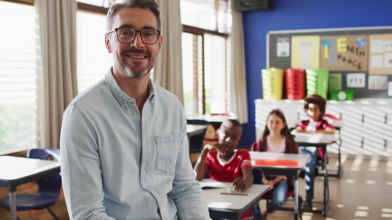 retrato de un feliz maestro caucásico en el aula con niños mirando a la cámara