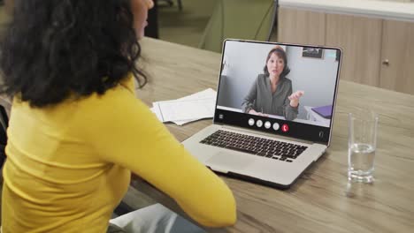 Mujer-Birracial-Usando-Una-Computadora-Portátil-Para-Videollamada,-Con-Un-Colega-De-Negocios-En-La-Pantalla