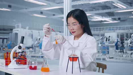 side view of asian woman scientist making experiment with test tube in the laboratory with microscope. carrying out experiments, working in the lab analyzing her finding samples test tube